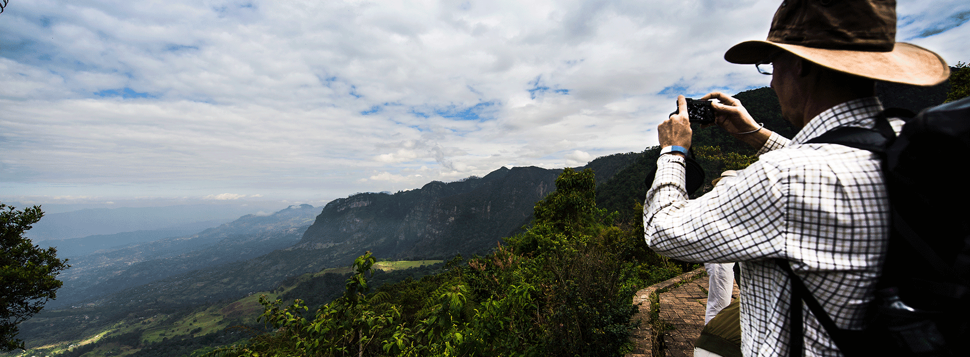 Turista fotografiando paisaje con montañas en Colombia