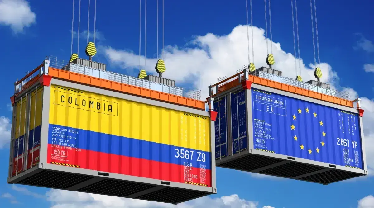 Contenedores de carga en el aire, uno con los colores de la bandera de Colombia, simbolizando comercio internacional.