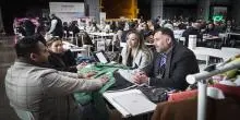 Grupo de personas hablando en una mesa en stand de feria sobre Macrorruedas
