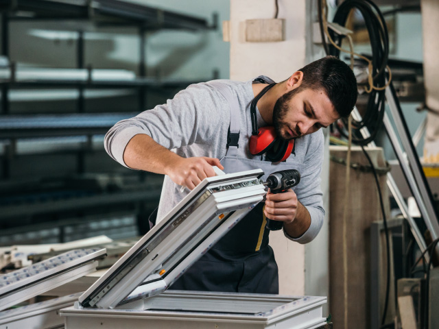 Colombia exporta aluminio con el que trabaja el hombre de la imagen, ya que exportar ventanas de aluminio es parte de las venta externas del país.