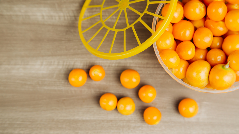 Goldenberries in their traditional packaging on a wooden table during the day.