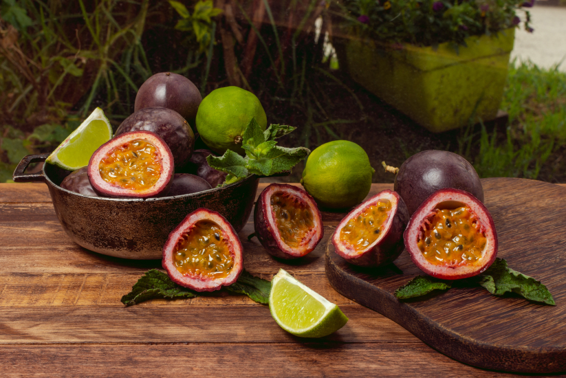 gulupa fresca en el exterior sobre una mesa de madera y plantas en la parte de atrás.